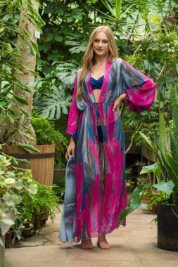 Tropik tatil köyünde yazlık giysiler giyen güzel genç bir kadın.