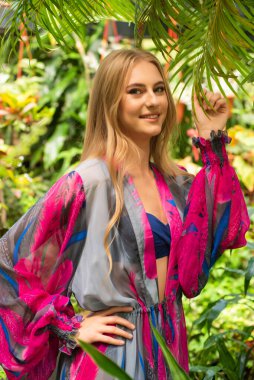 Tropik tatil köyünde yaz kıyafetleri giyen bir kadın.