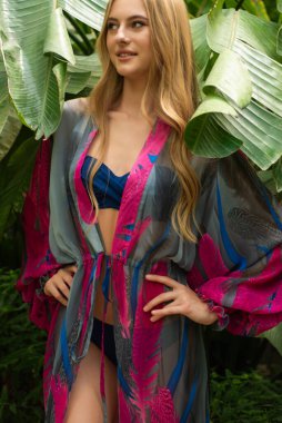 Tropik tatil köyünde yaz kıyafetleri giyen bir kadın.