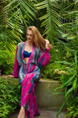 Tropik tatil köyünde yaz kıyafetleri giyen bir kadın.