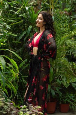 Tropik tatil köyünde yazlık giysiler giyen güzel genç bir kadın.