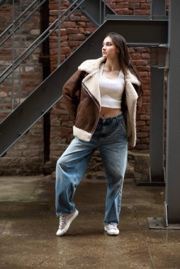 Sokakta poz veren sıradan giyinmiş genç bir kadın.