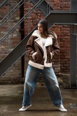 Sokakta poz veren sıradan giyinmiş genç bir kadın.