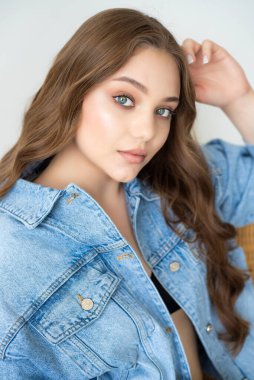 Gri arka planda poz veren kot pantolon ve kot ceketli genç ve güzel bir kız. moda yaşam tarzı ve insanlar