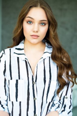 Uzun kıvırcık saçlı ve mavi gözlü güzel bir kızın portresi.