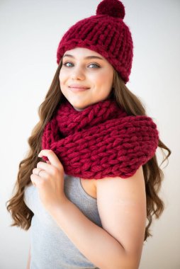 Kırmızı örgü şapkalı ve atkılı kadın. Moda ve tarz kavramı. Örgü örmüş bir kızın stüdyo fotoğrafı.