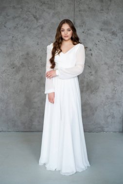 Uzun saçlı, beyaz gelinlikli genç kadın.