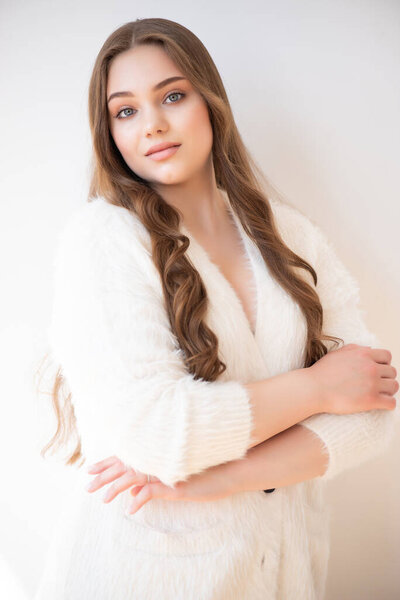 портрет молодой женщины в белом свитере на белом фоне.