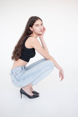 Siyah bluzlu ve kot pantolonlu genç bir esmerin portresi.