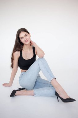 Beyaz zeminde oturan güzel genç bir kadının portresi.