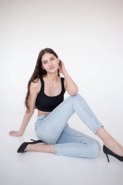 Stüdyoda beyaz arka planda poz veren uzun saçlı genç kız..