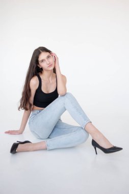 Güzel esmer kadın beyaz arka planda oturuyor.