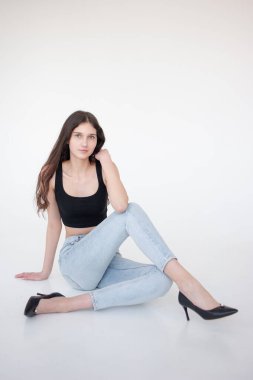 Siyah bluzlu genç kadın ve beyaz arka planda kot pantolon.