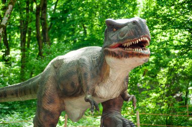 Yeşil ağaçların arkasındaki büyük dinozor.