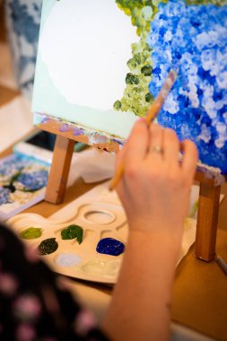 Sanatçı stüdyoda tuvale fırça çizer..