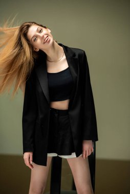 Gri arka planda siyah takım elbiseli güzel bir kız.
