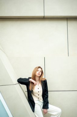 Büyük bir iş merkezinin arka planında beyaz takım elbiseli güzel bir genç kız.