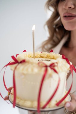 Genç kadın pastayla mum üflüyor.