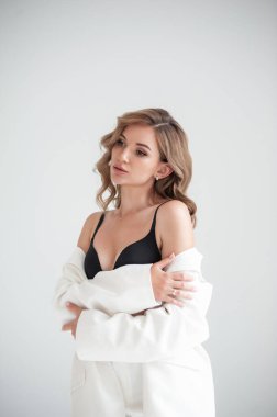 Beyaz bluzlu, siyah sütyenli ve göğsünde beyaz gömlekli bir kadın.