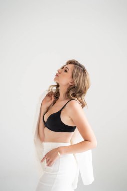 Beyaz sütyenli ve siyah pantolonlu kadın.