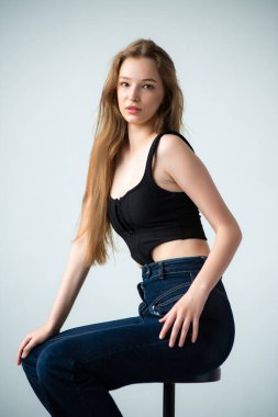 Siyah bluzlu, siyah arka planda güzel bir sarışının portresi.