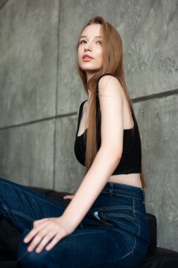 Siyah desenli arka planda beyaz gömlekli, uzun kızıl saçlı güzel bir kızın portresi.