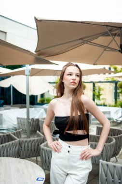 Siyah deri pantolonlu ve mavi gömlekli güzel bir kadın. Moda kızı şehirde bir kafe yakınında poz veriyor.