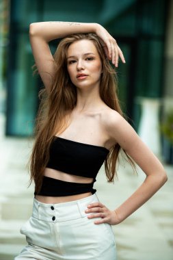 Beyaz gömlek ve şortla poz veren güzel genç bir kadın.