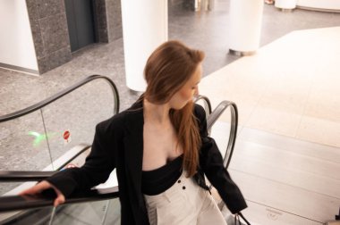 Yürüyen merdivenli beyaz elbiseli güzel bir kız.