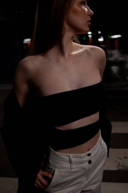 Gece sokakta poz veren siyah elbiseli güzel bir kız.