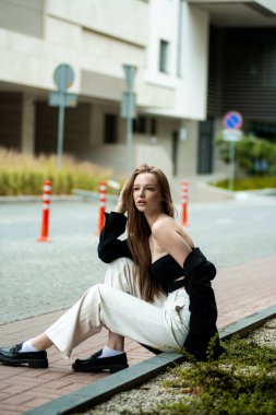 Güzel, modaya uygun bir kız sokakta poz veriyor.