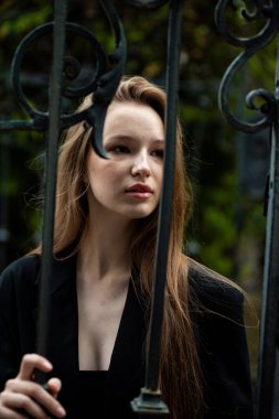 Dışarıda poz veren siyah paltolu güzel bir kadın. Sonbahar parkında siyah saçlı bir kızın portresi..