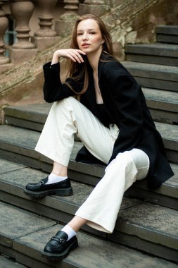 Taş bir merdivenin basamaklarında genç bir kadının portresi.