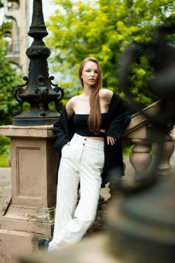 Parktaki bankta oturan ve kameraya bakan genç ve güzel bir kadın..