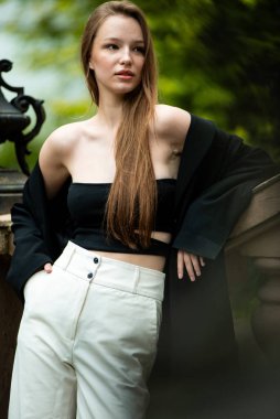 Beyaz bluzlu ve siyah pantolonlu güzel bir kız şehirde poz veriyor.