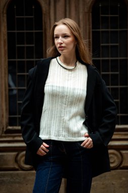 Kahverengi gözlü, beyaz bluzlu ve siyah kotlu kız..