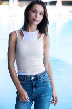 Açık havada poz veren kot pantolonlu güzel bir kadının portresi.