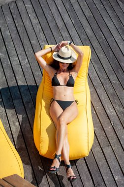 Plajda hamakta oturan siyah mayolu güzel bir bayan.