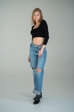 Güzel saçlı ve kot pantolonlu genç bir kızın tam vücut fotoğrafı.