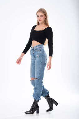 Siyah bluzlu ve beyaz arka planda poz veren bir kızın tam boy portresi..