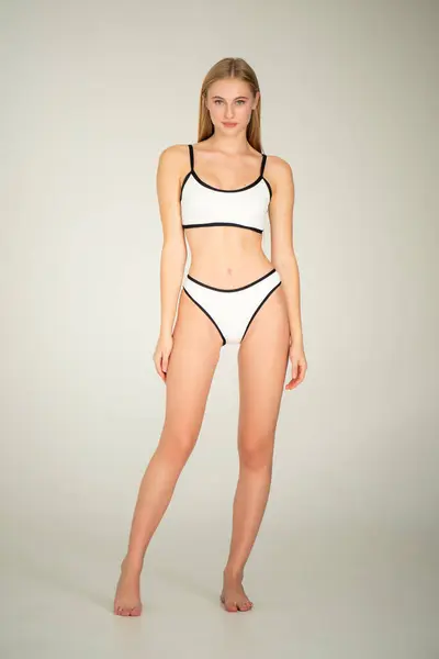 Beyaz iç çamaşırlı kadın beyaz arka planda poz veriyor..