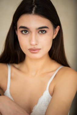 Evde poz veren beyaz gözlü ve çıplak omuzlu çekici esmer kız portresi..