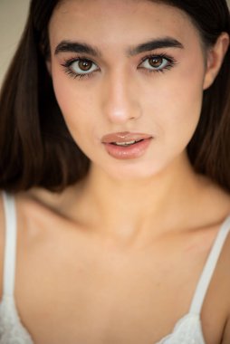 Gri arka planda beyaz makyajlı bir kadının portresi.