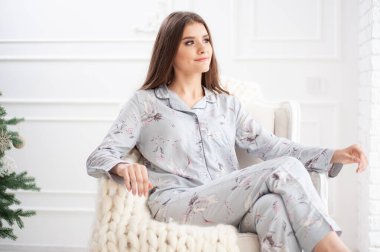 Evdeki kanepede oturan genç bir kadın.