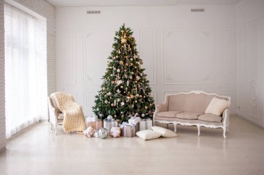 Elegant Christmas interior with a decorated tree in gold and white, wrapped gifts, a vintage beige sofa, and an armchair with a cozy knit blanket. Bright white walls create a festive, minimalist ambiance clipart