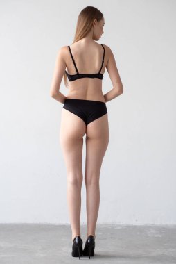 Genç ve güzel bir kız siyah iç çamaşırlarıyla dikiliyor.