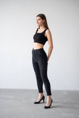 Siyah saçlı, beyaz arka planda gri tişörtlü genç bir kız..