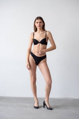 İç çamaşırlı genç bir kız hafif arka planda poz veriyor.