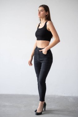 Esmer bir kadının uzun bir portresi. Günlük kıyafetler ve siyah bluz giyiyor. duruş beyaz arkaplan üzerinde izole.