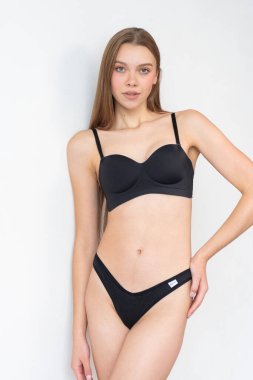 Basit siyah iç çamaşırlı, taze yüzlü bir mankenin görüntüsü. Doğal özelliklerini, vücut oranlarını ve kendine güvenen duruşunu vurguluyor. Ajans keşifleri ve profesyonel portföy güncellemeleri için ideal